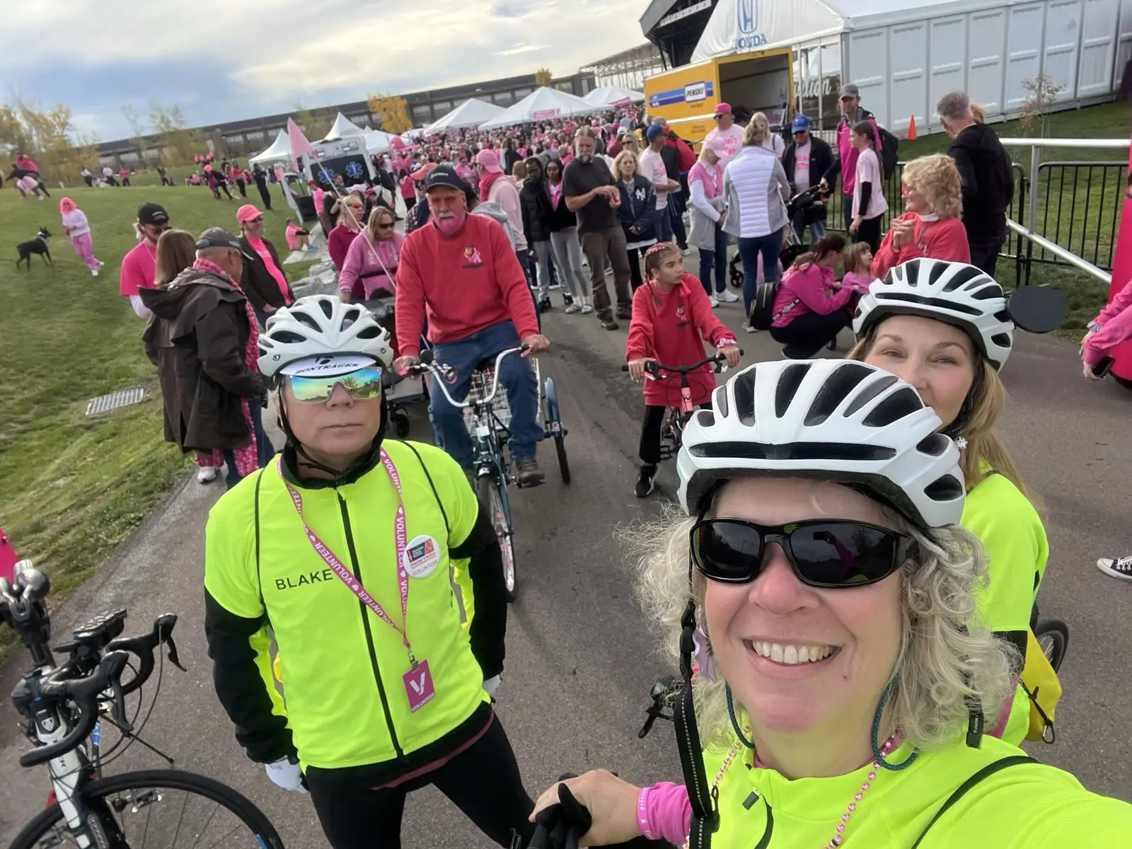 A selfie taken by one of our event marshals of several of our marshals right before a charity ride for breast cancer awareness, a large crowd of participants behind them