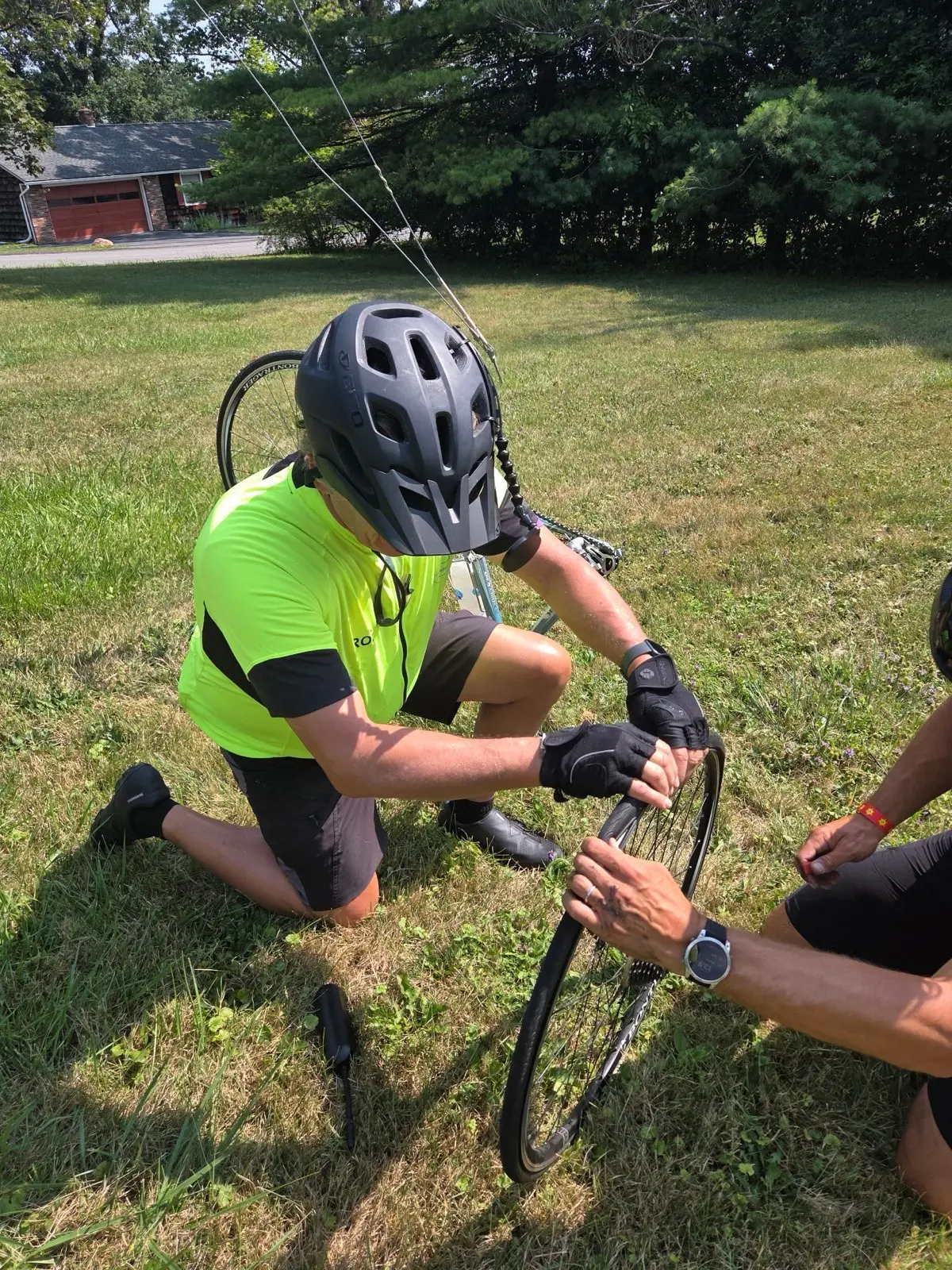One of our event marshals inspecting and fixing a bike tire while someone else holds it