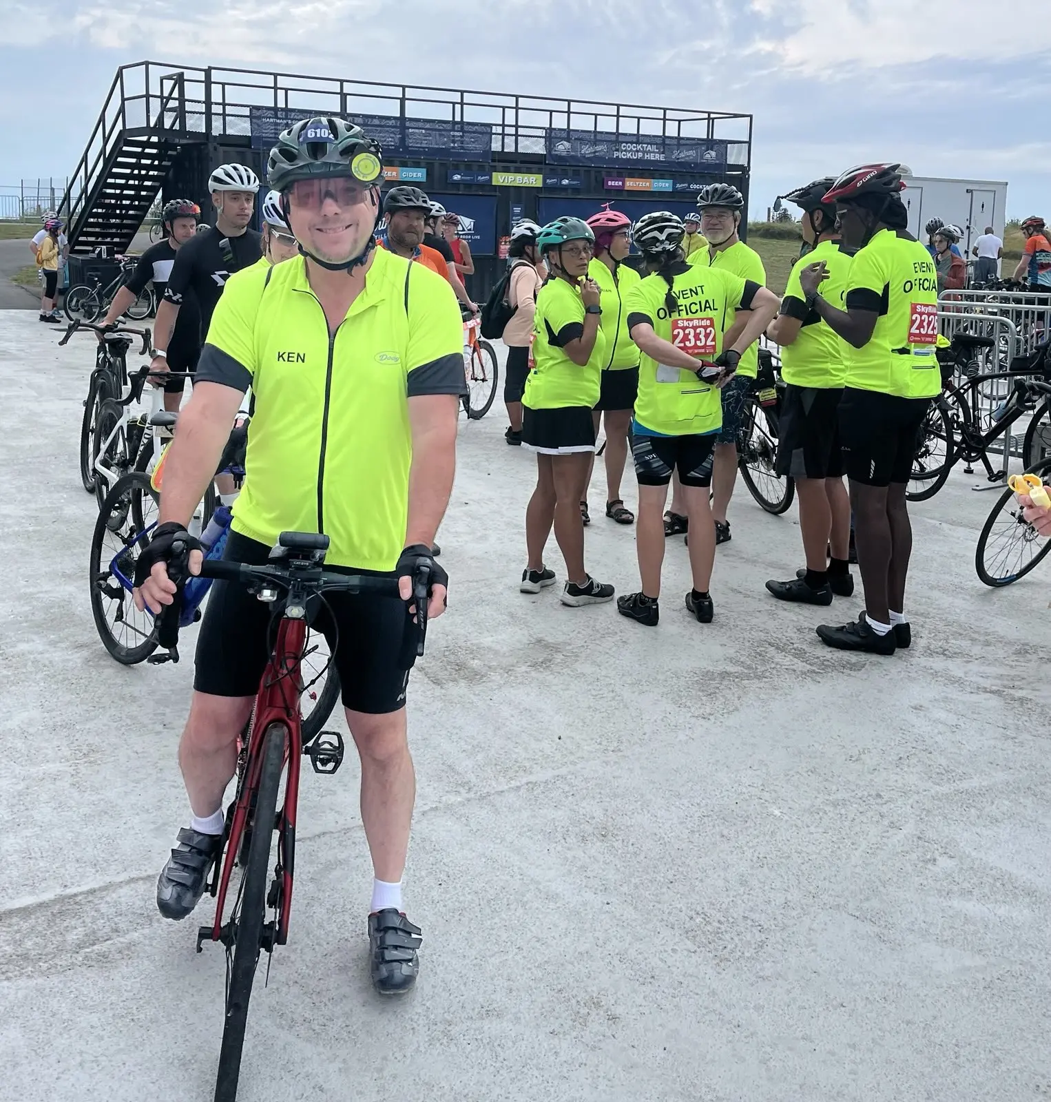 One of our event marshals on his bike smiling at the camera while a group of marshals behind him converses